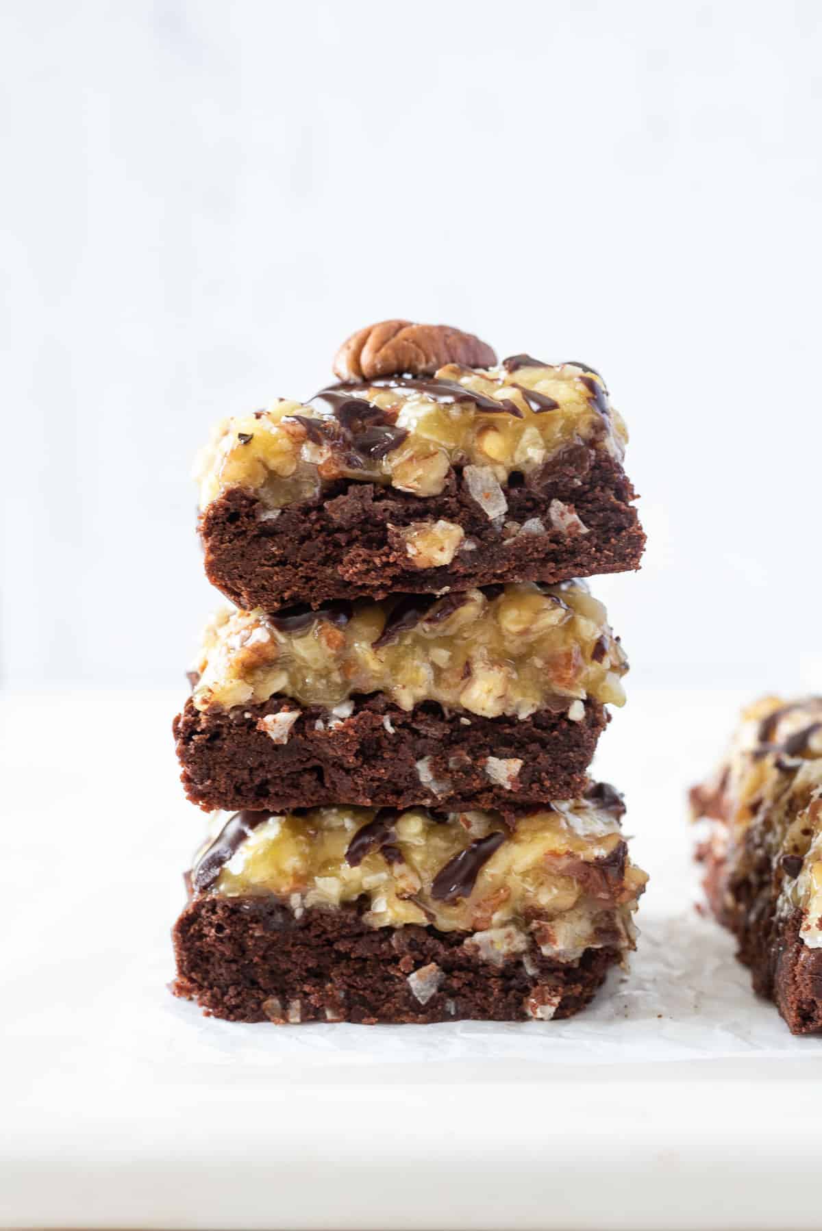 A close up side view of a stack of German chocolate brownies on a white counter.