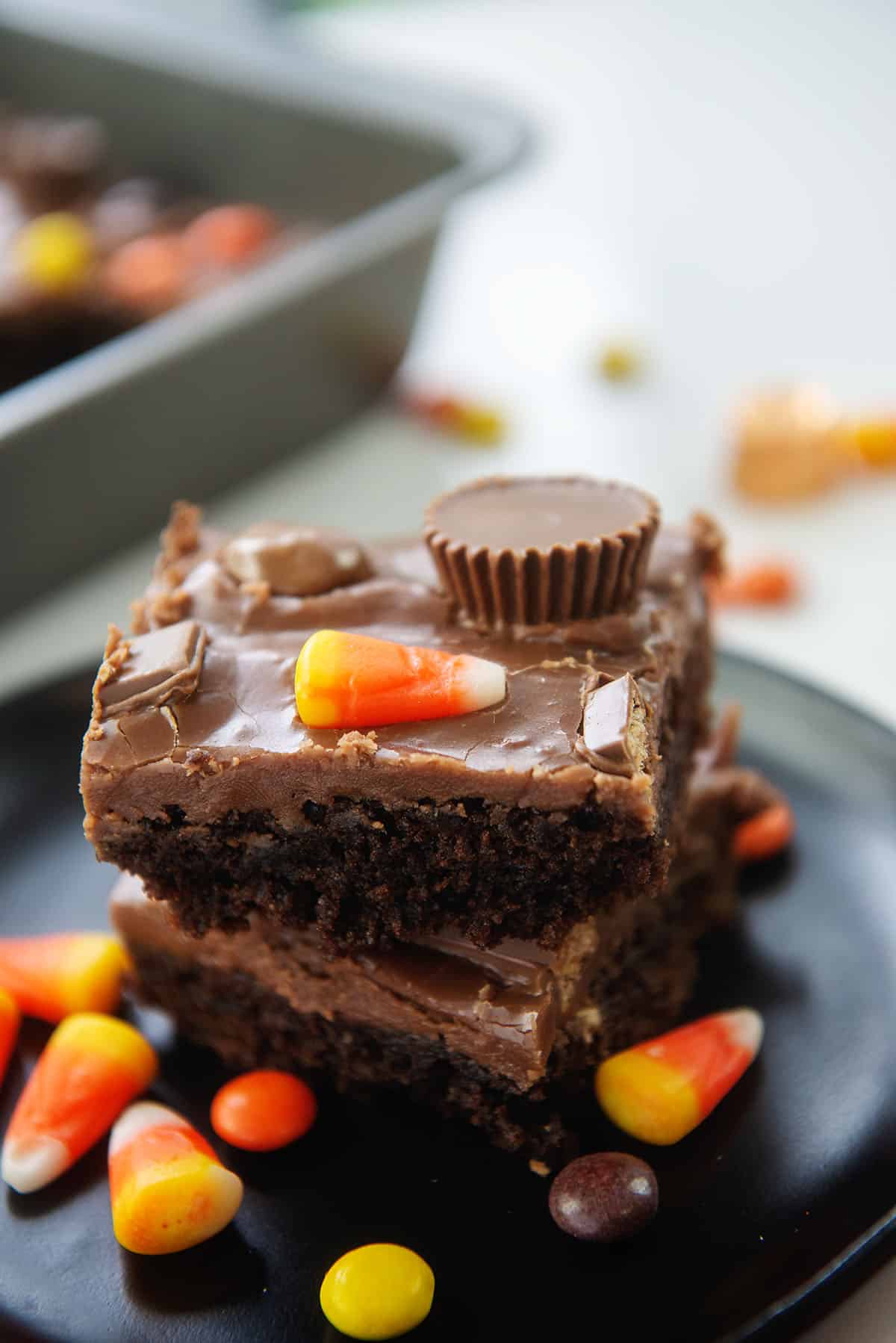 frosted brownies with candy on black plate.