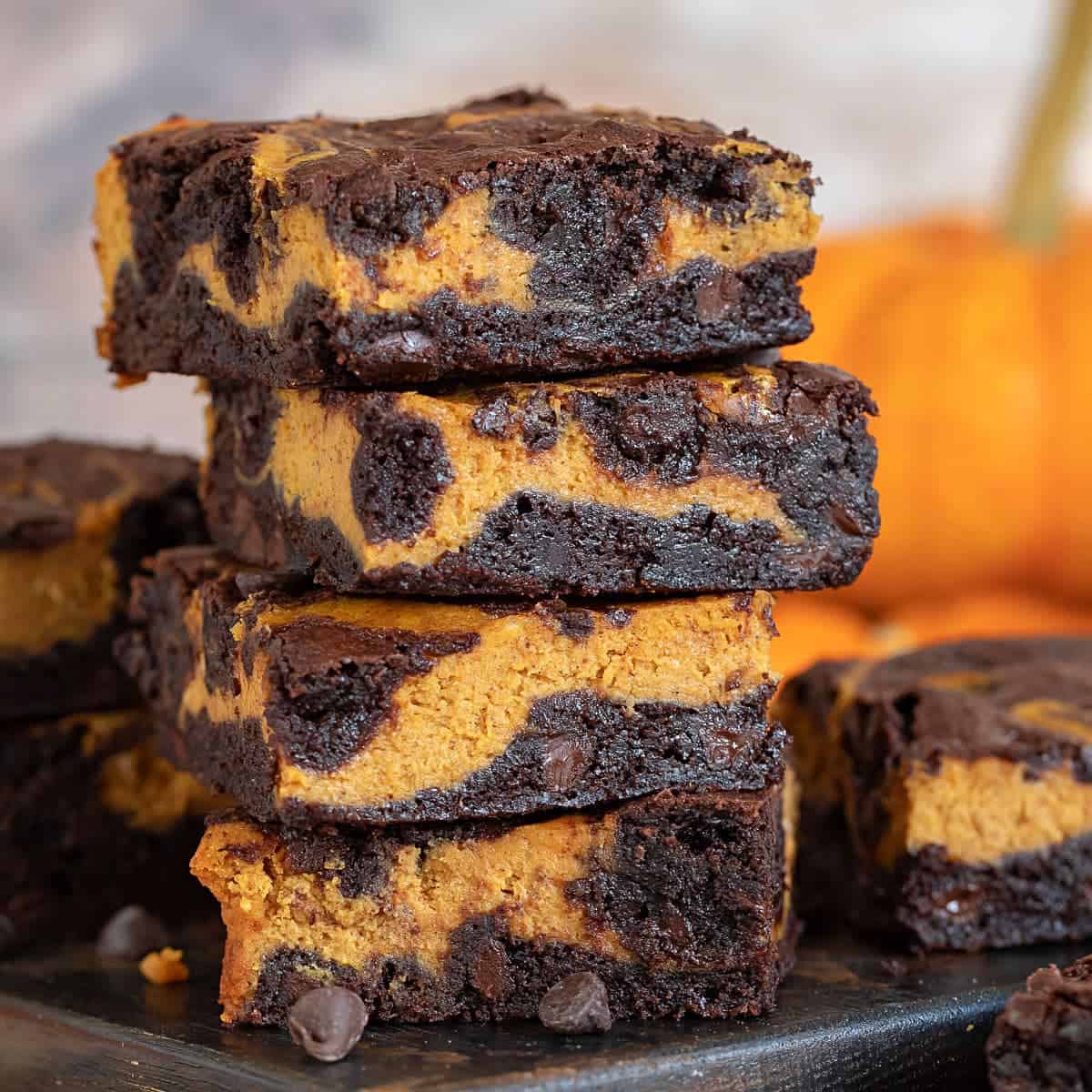 A close up view of a stack of chocolate pumpkin brownies and chocolate chips.