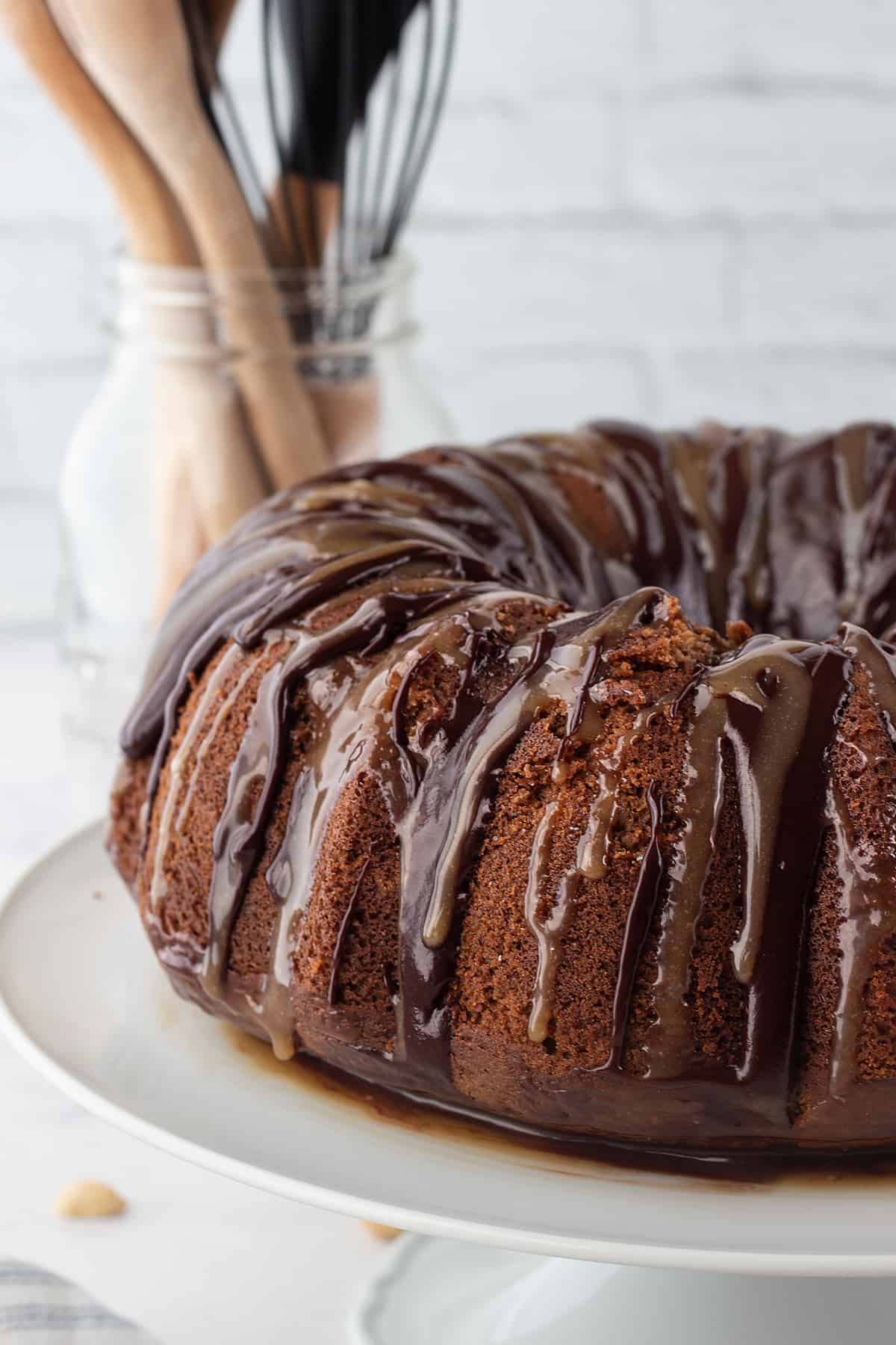 chocolate bundt cake drizzled with glaze on cake stand.