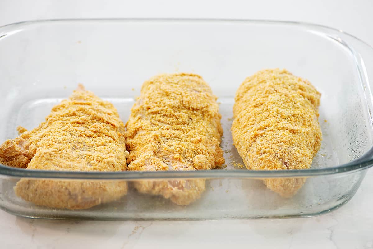 chicken coated in Ritz cracker crumbs in baking dish.