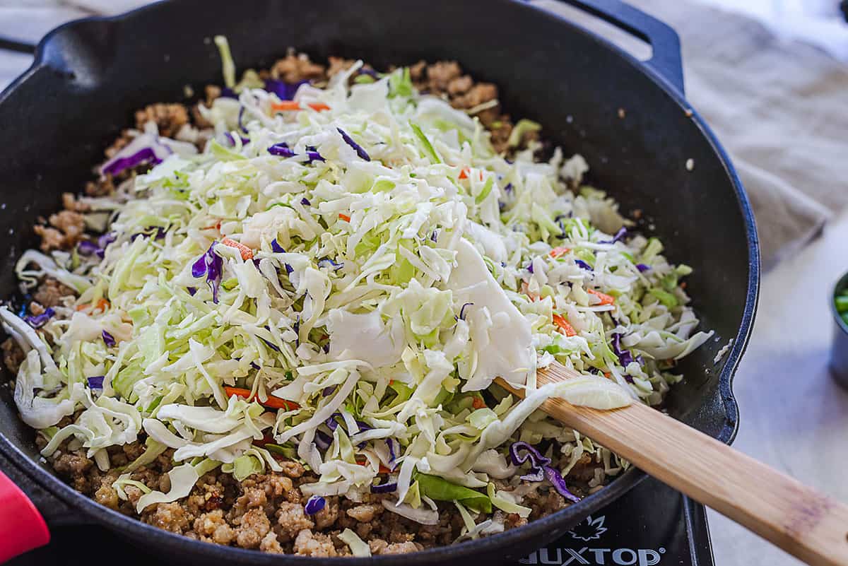 cabbage in skillet with sausage.