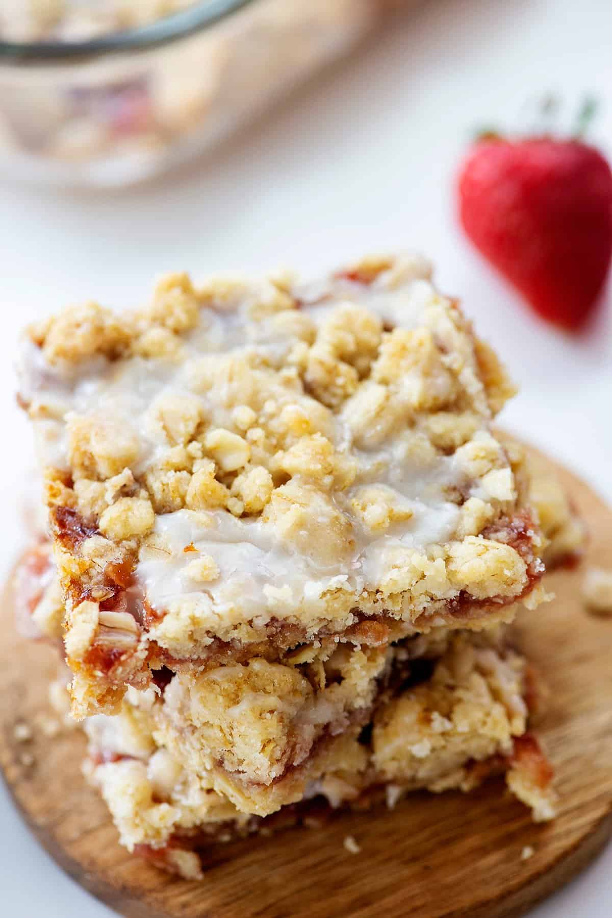 strawberry oatmeal bars stacked on small wooden board.