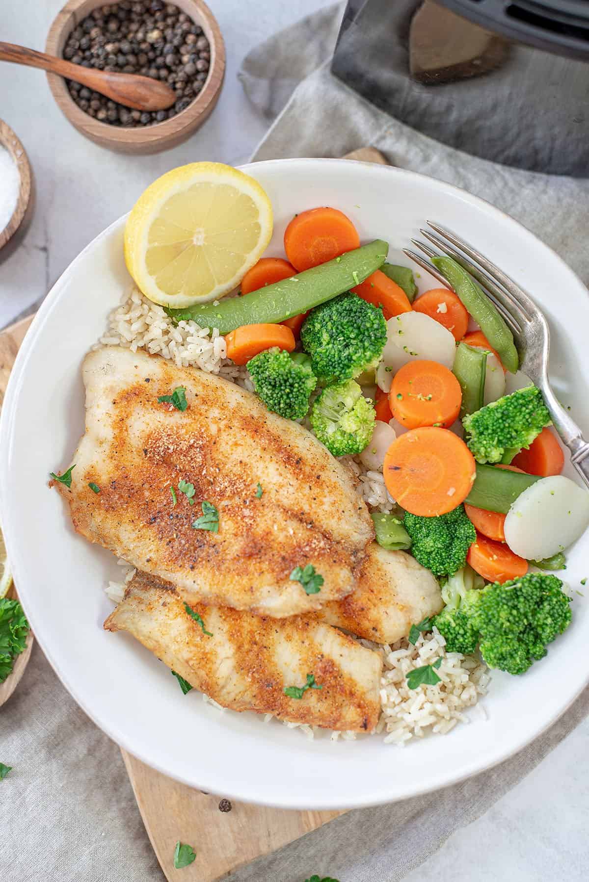 overhead view of air fryer tilapia in bowl with rice and veggies.