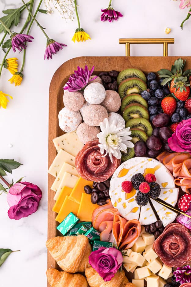 charcuterie board surrounded by flowers for mother's day.