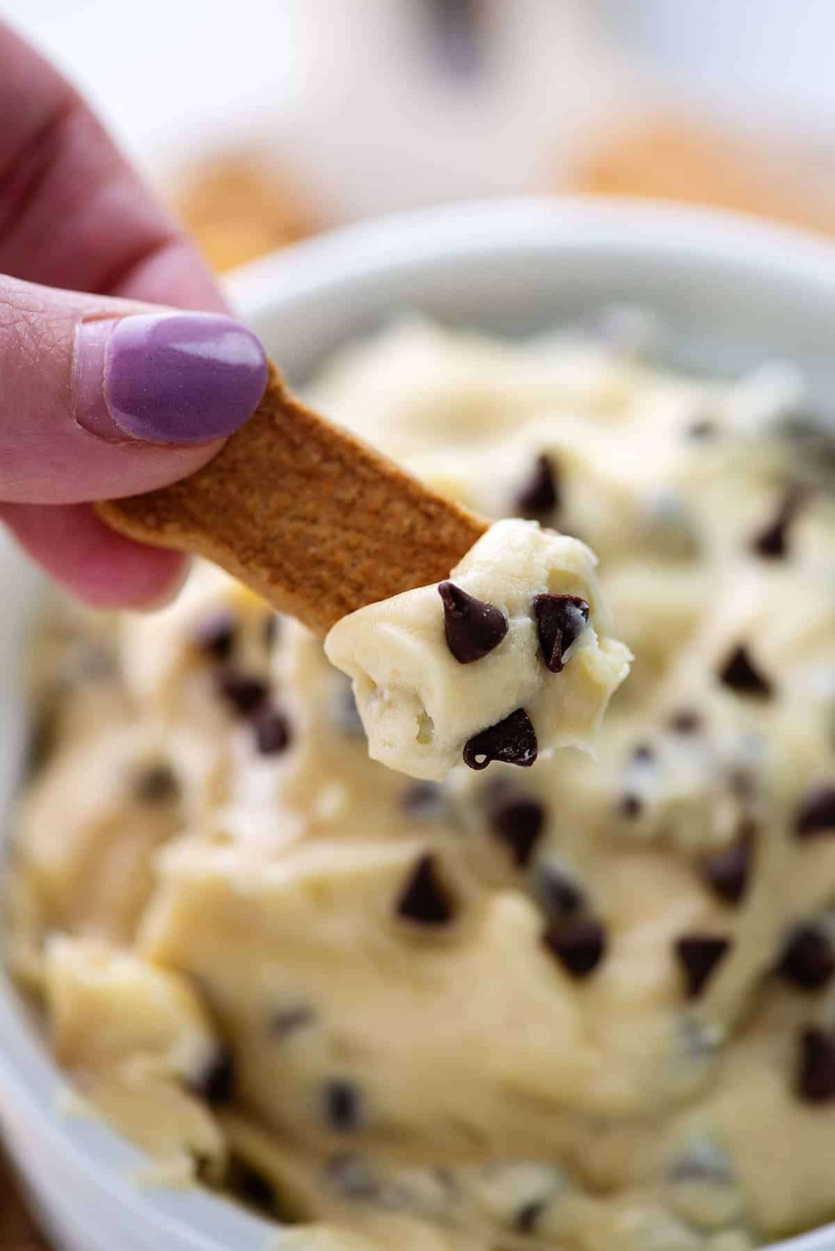 hand holding a graham cracker stick dipped in cookie dough dip.
