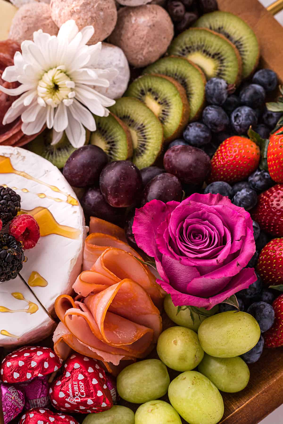 charcuterie board with fresh fruit and flowers.