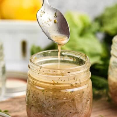 Greek dressing dripping off spoon into jar.