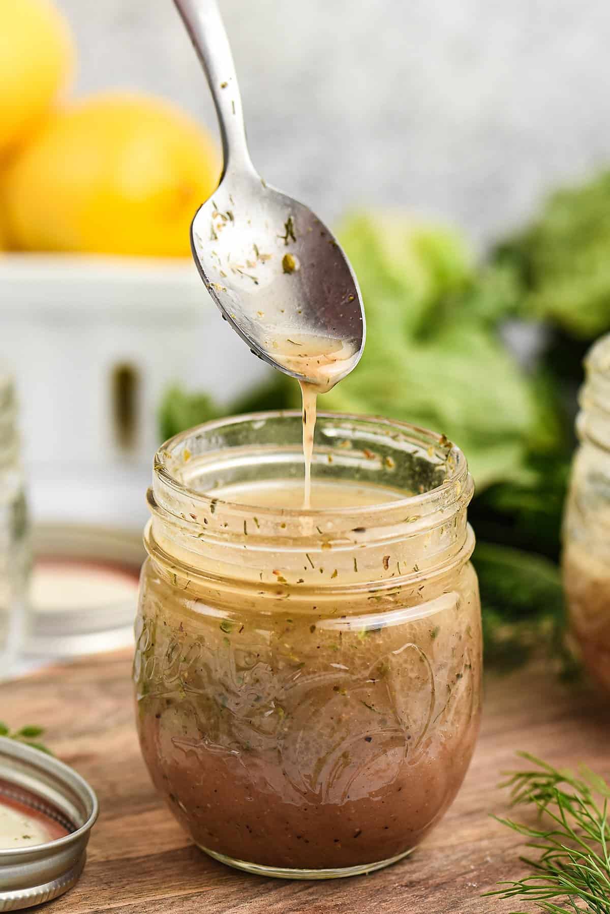 Greek dressing dripping off spoon into jar.