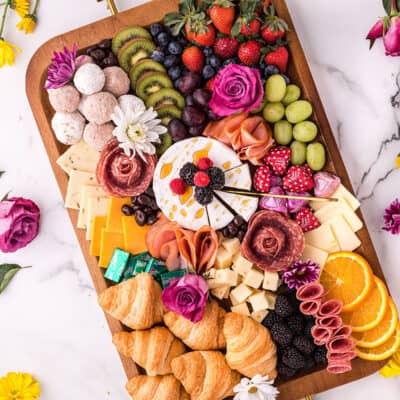 Mother's Day charcuterie board surrounded by flowers.