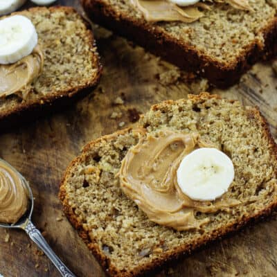 Slices of banana bread with peanut butter and banana on top.
