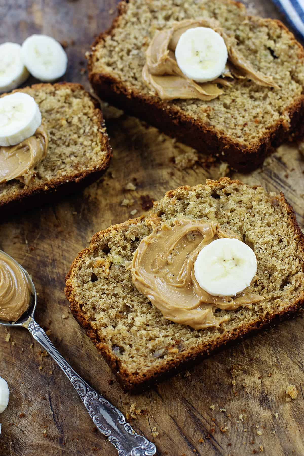 Slices of banana bread with peanut butter and banana on top.