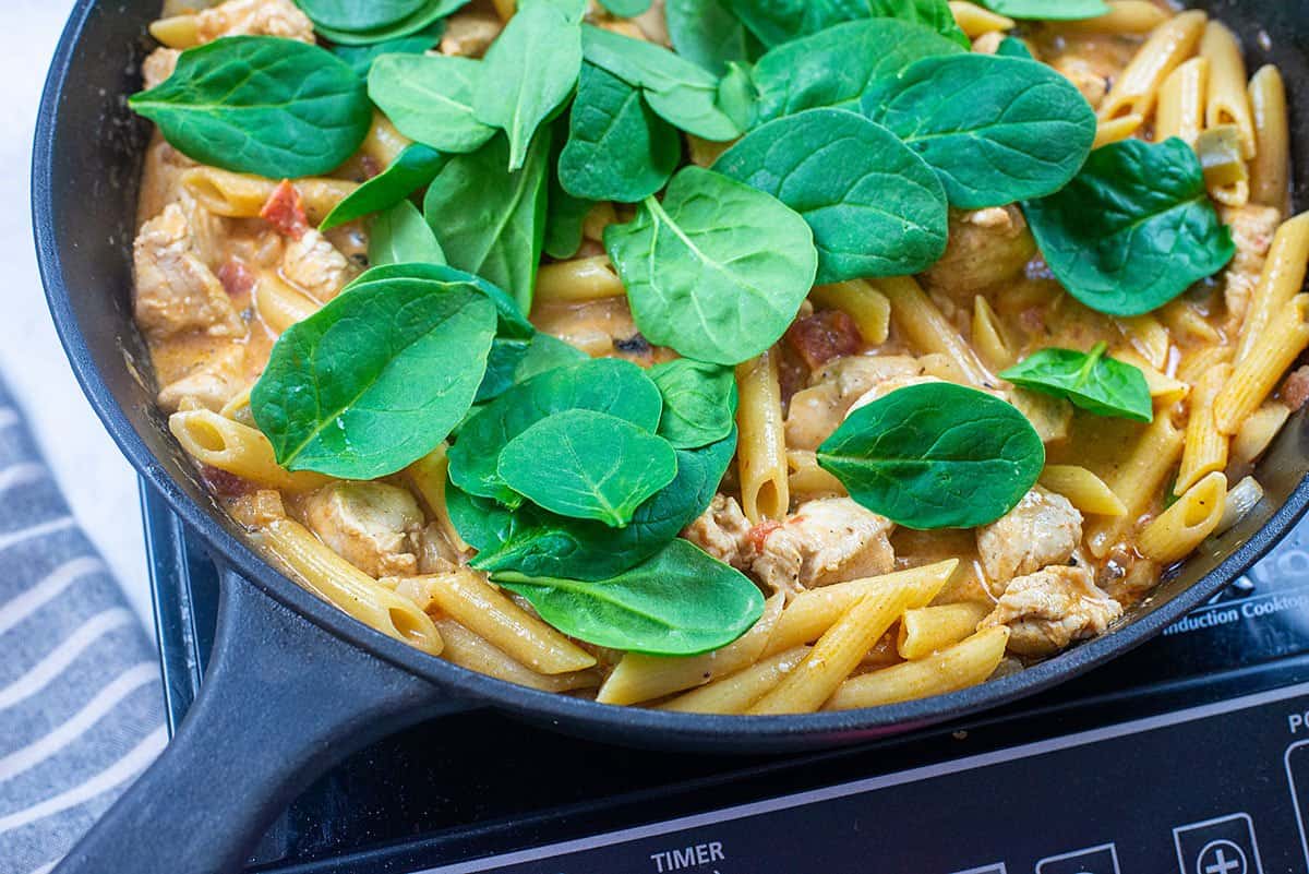 spinach and pasta in skillet.