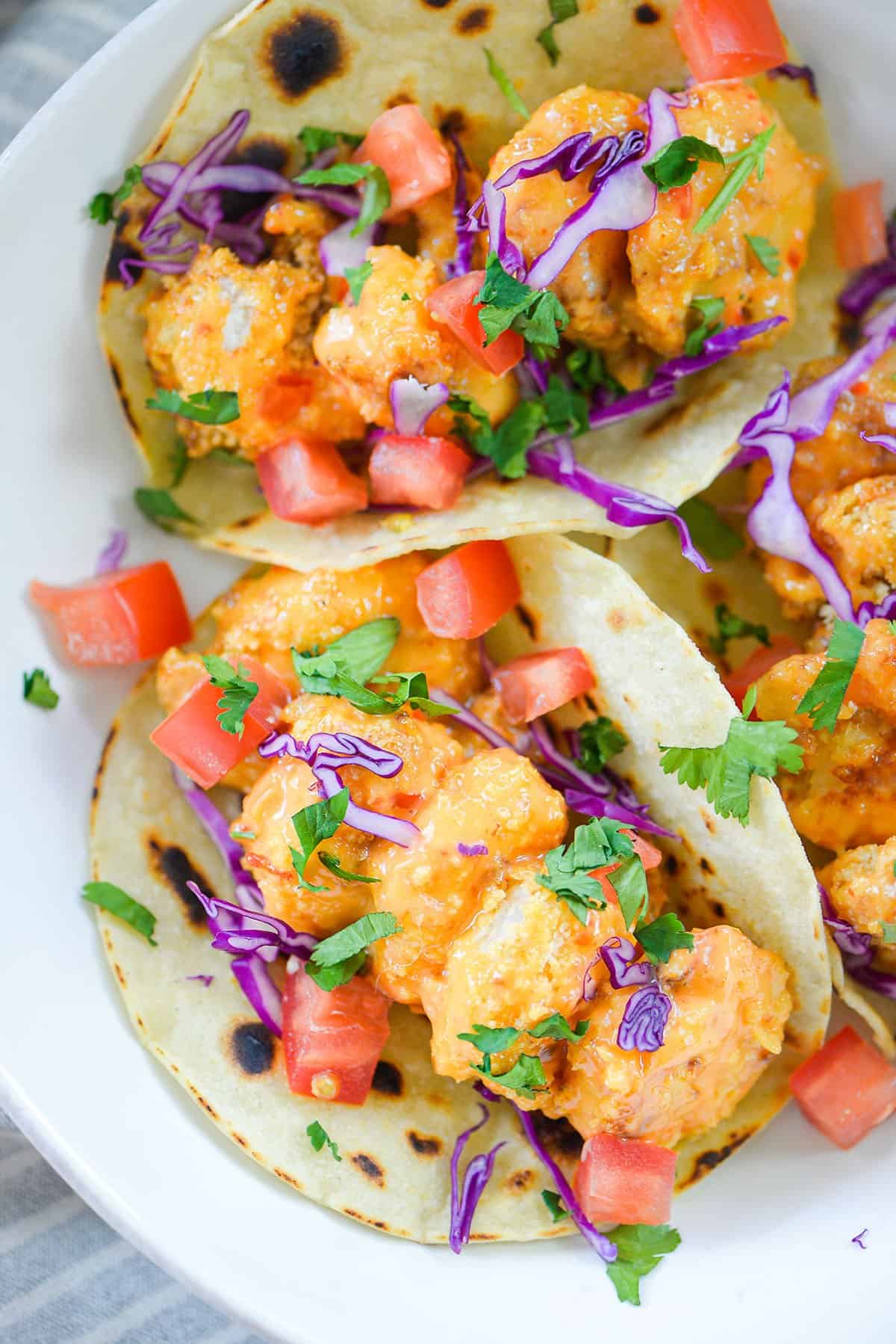 bang bang shrimp tacos on white plate.