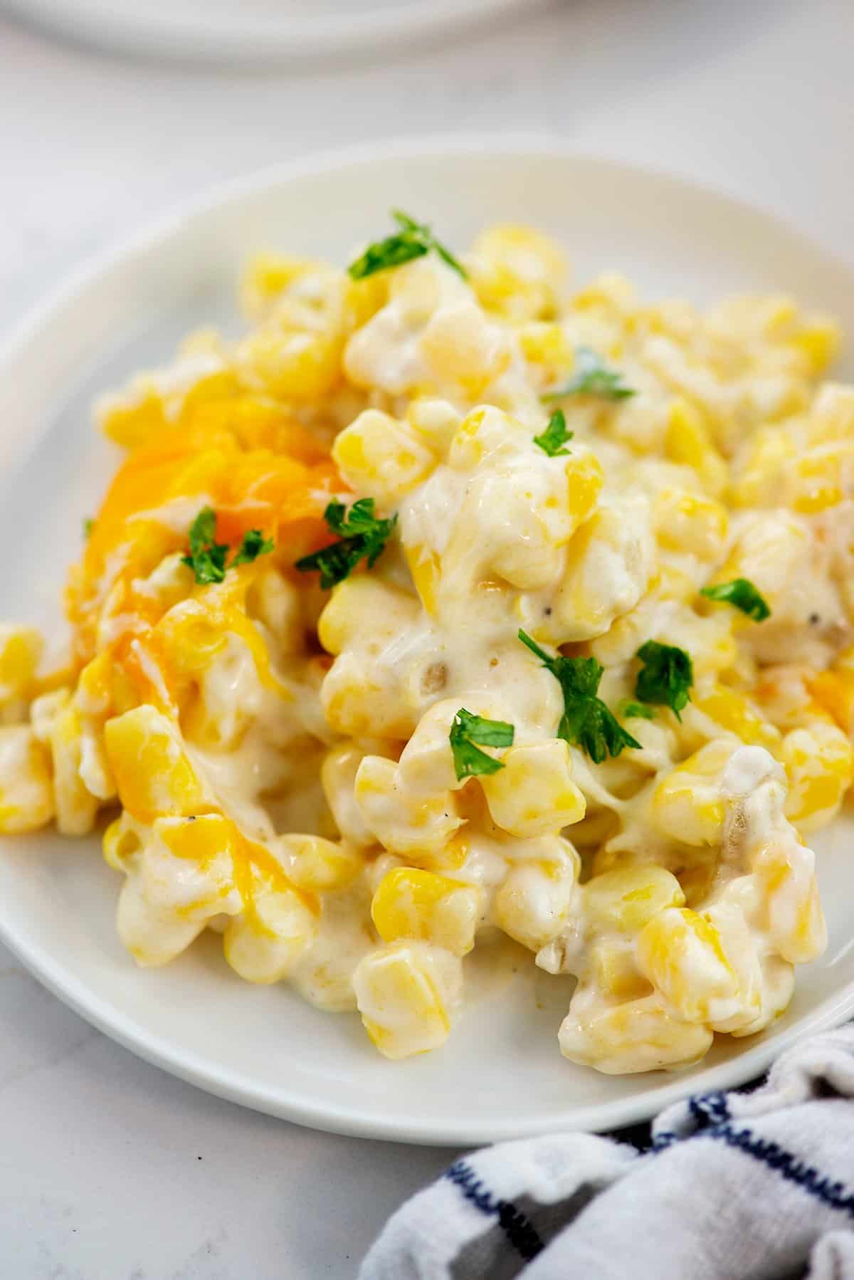 close up photo of cream cheese corn casserole on white plate.