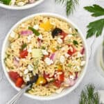Greek orzo pasta salad in bowlw ith fork.