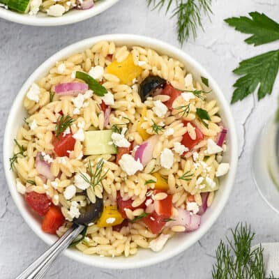 Greek orzo pasta salad in bowlw ith fork.