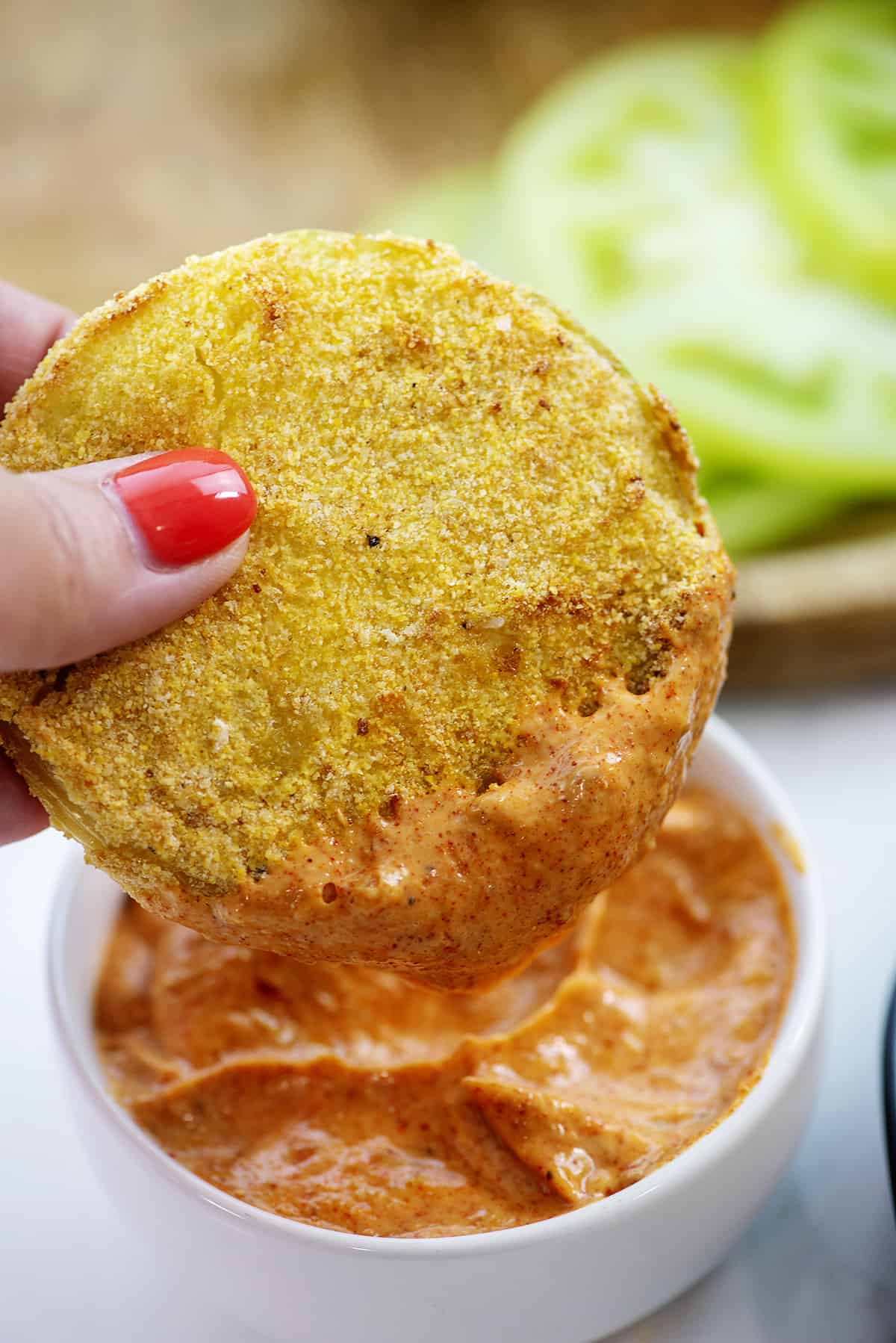 fried green tomato being dipped in sauce.