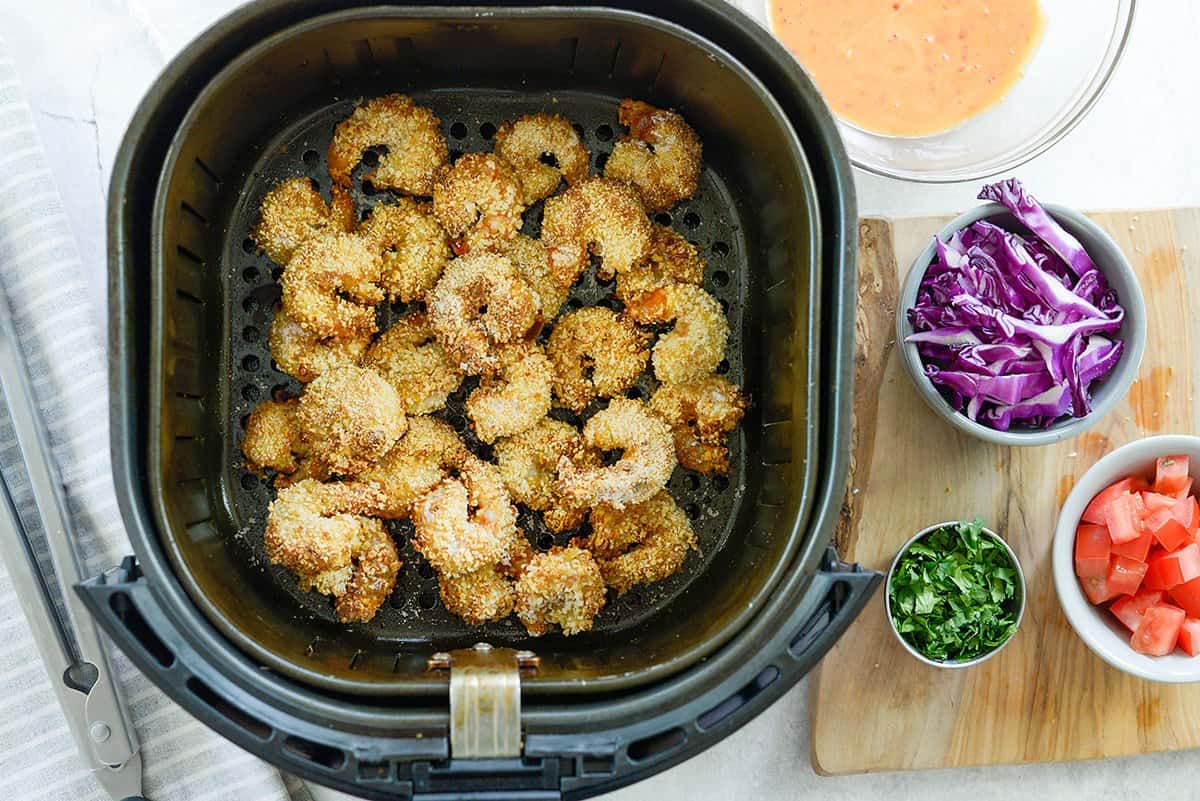 fried shrimp in air fryer basket.