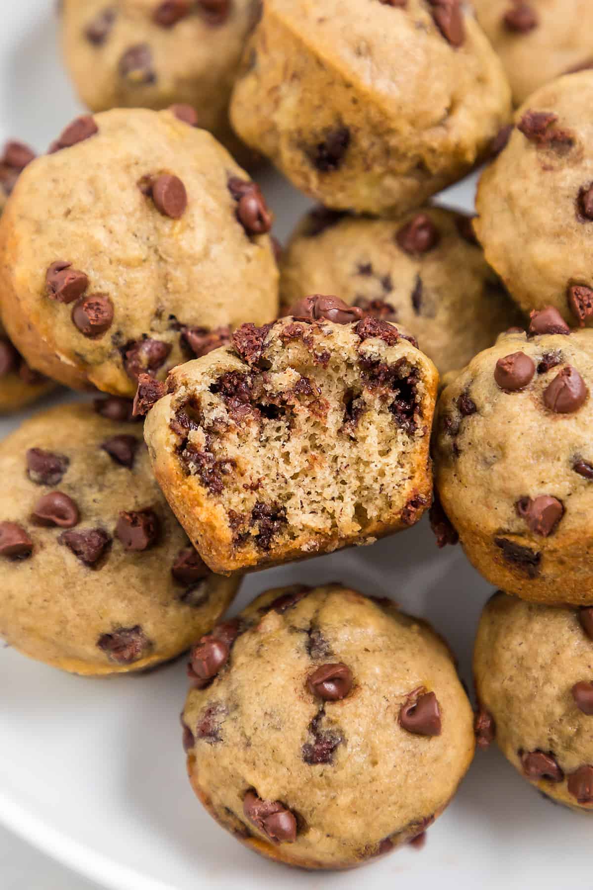 Mini banana muffins piled on white plate.