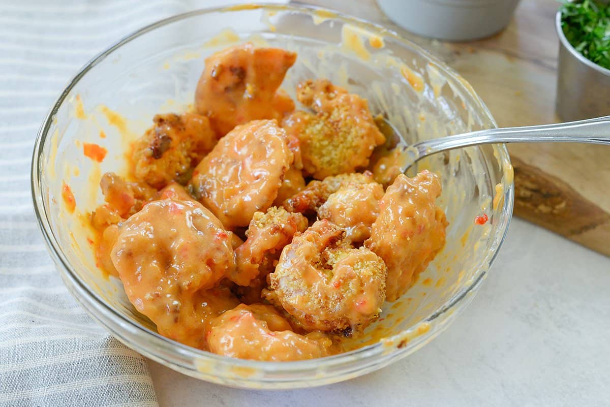 shrimp tossed in bang bang sauce in glass bowl.