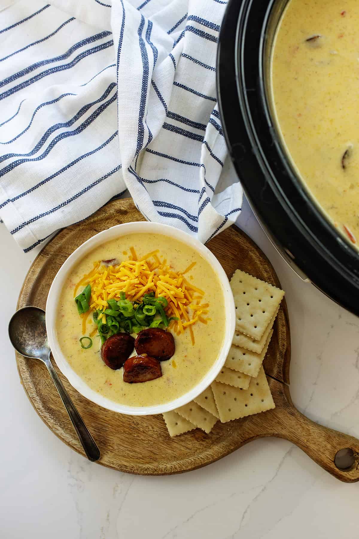 Overhead view of Cajun potato soup in bowl next to crockpot.