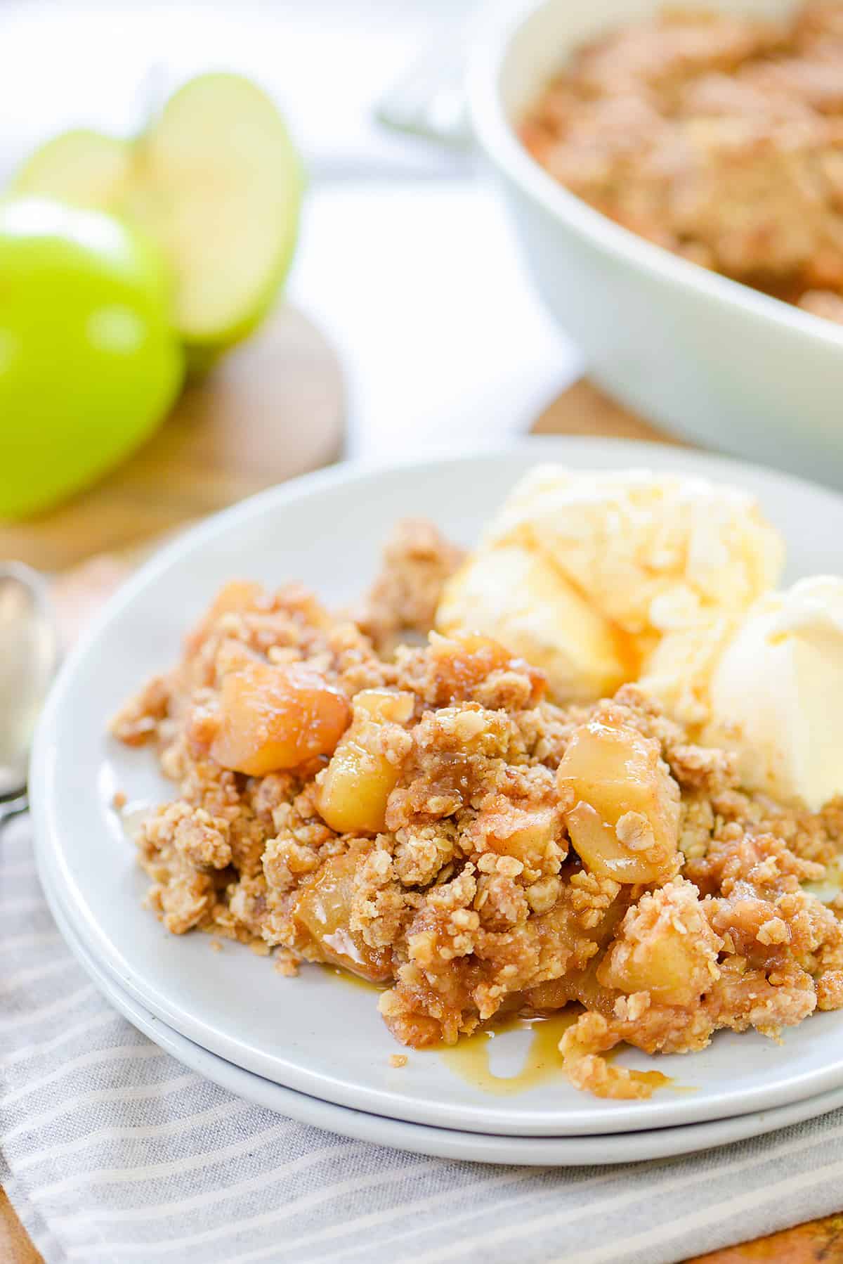 apple crumble with vanilla ice cream on small white plates.