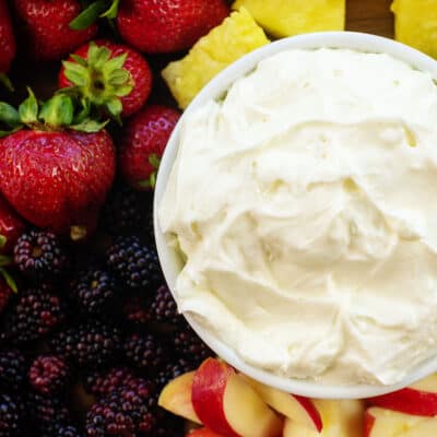 overhead view of cream cheese fruit dip in white bowl surrounded by fruit.