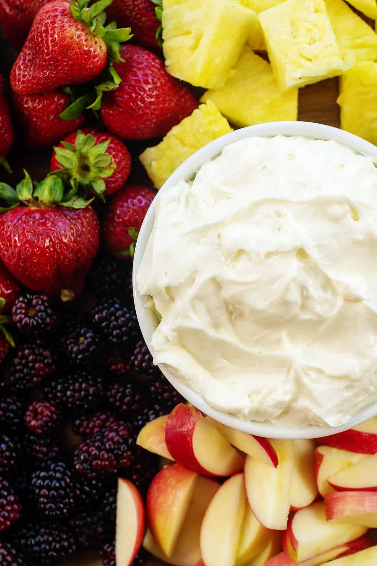 overhead view of cream cheese fruit dip in white bowl surrounded by fruit.