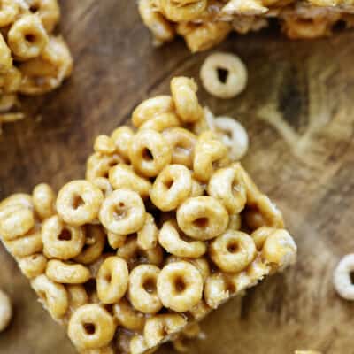 overhead view of peanut butter cheerio bars on wooden cutting board.