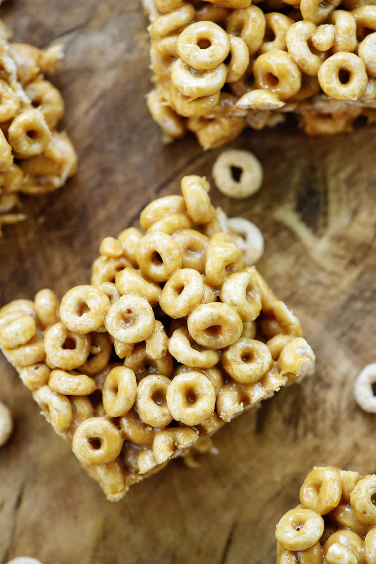 overhead view of peanut butter cheerio bars on wooden cutting board.