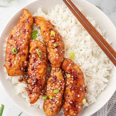 Chicken tenders coated in honey garlic sauce and served over bowl of white rice.