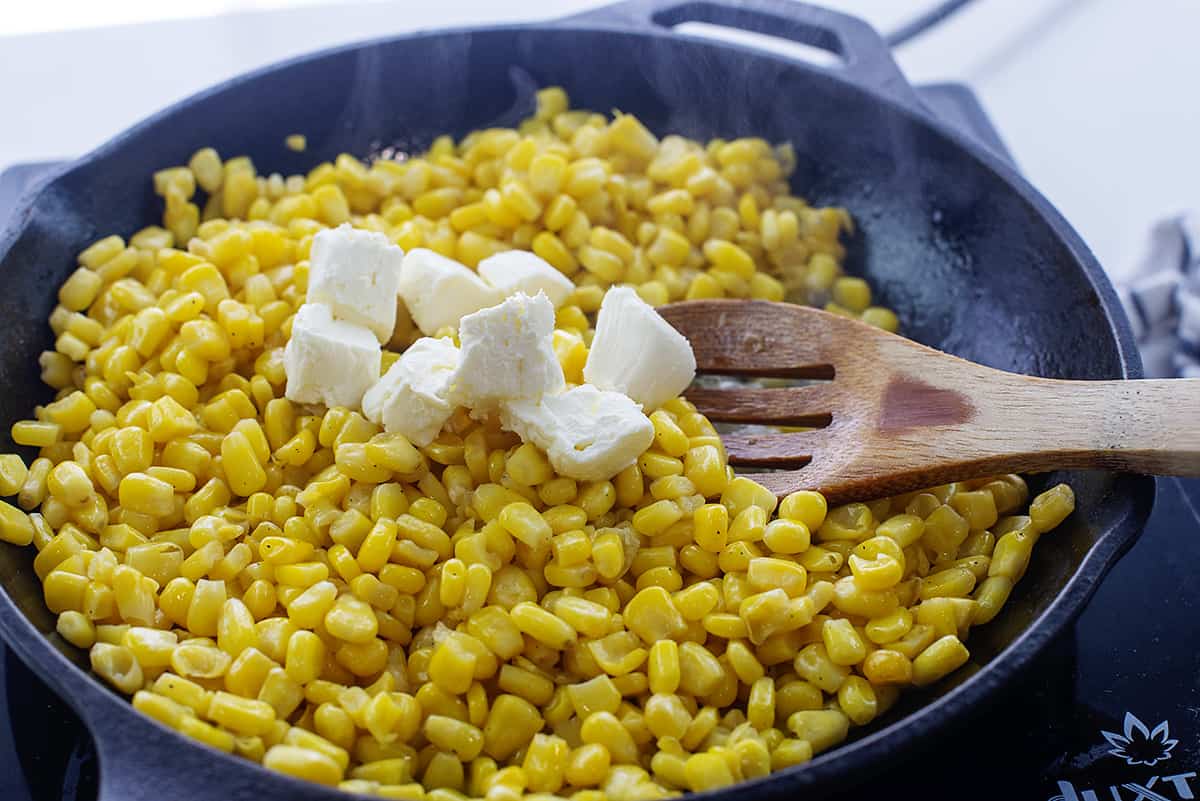 Cubed cream cheese over corn in skillet.