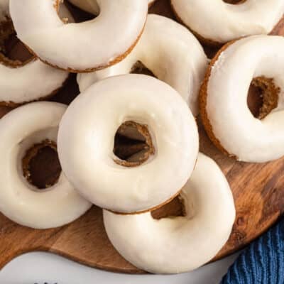 glazed donuts stacked on wooden board.