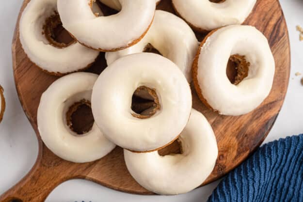 glazed donuts stacked on wooden board.
