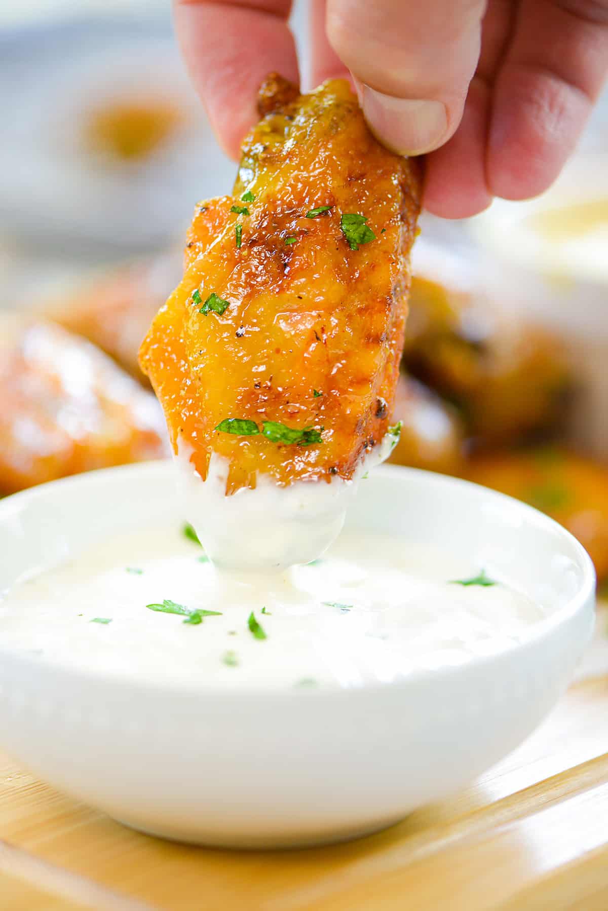 Honey mustard wing being dipping into ranch.