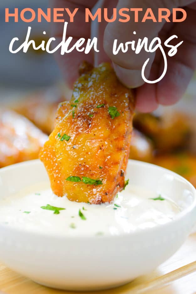 Hand dipping a chicken wing in ranch dressing.