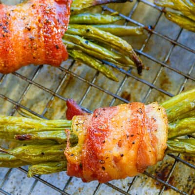 Green beans wrapped in bacon on wire rack.