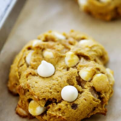 pumpkin cookie studded with white chocolate chips on baking sheet.