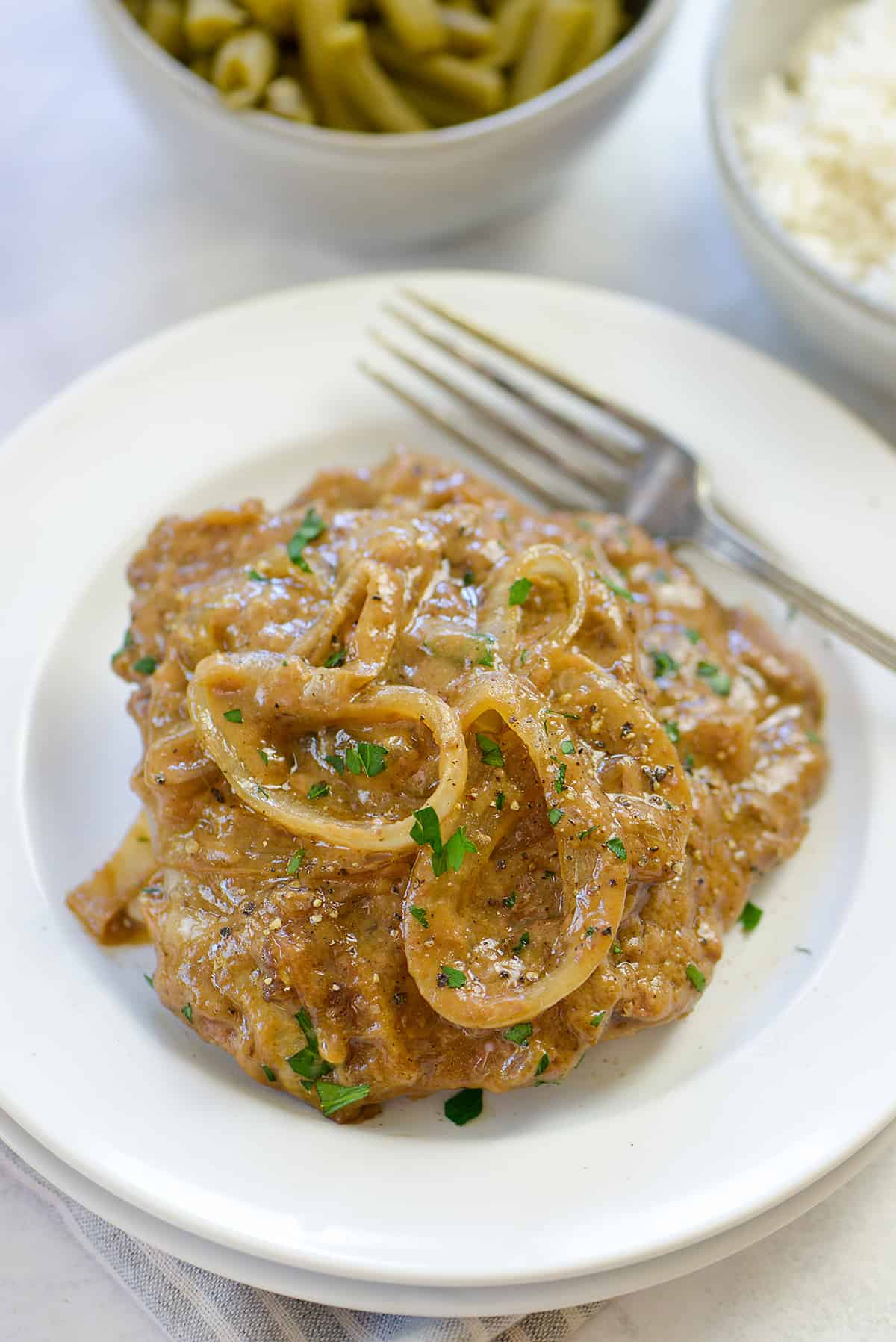 Cube steak smothered in gravy on small white plate.