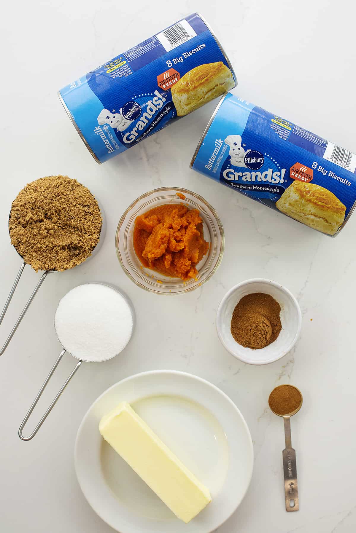 Pumpkin monkey bread ingredients on white counter.