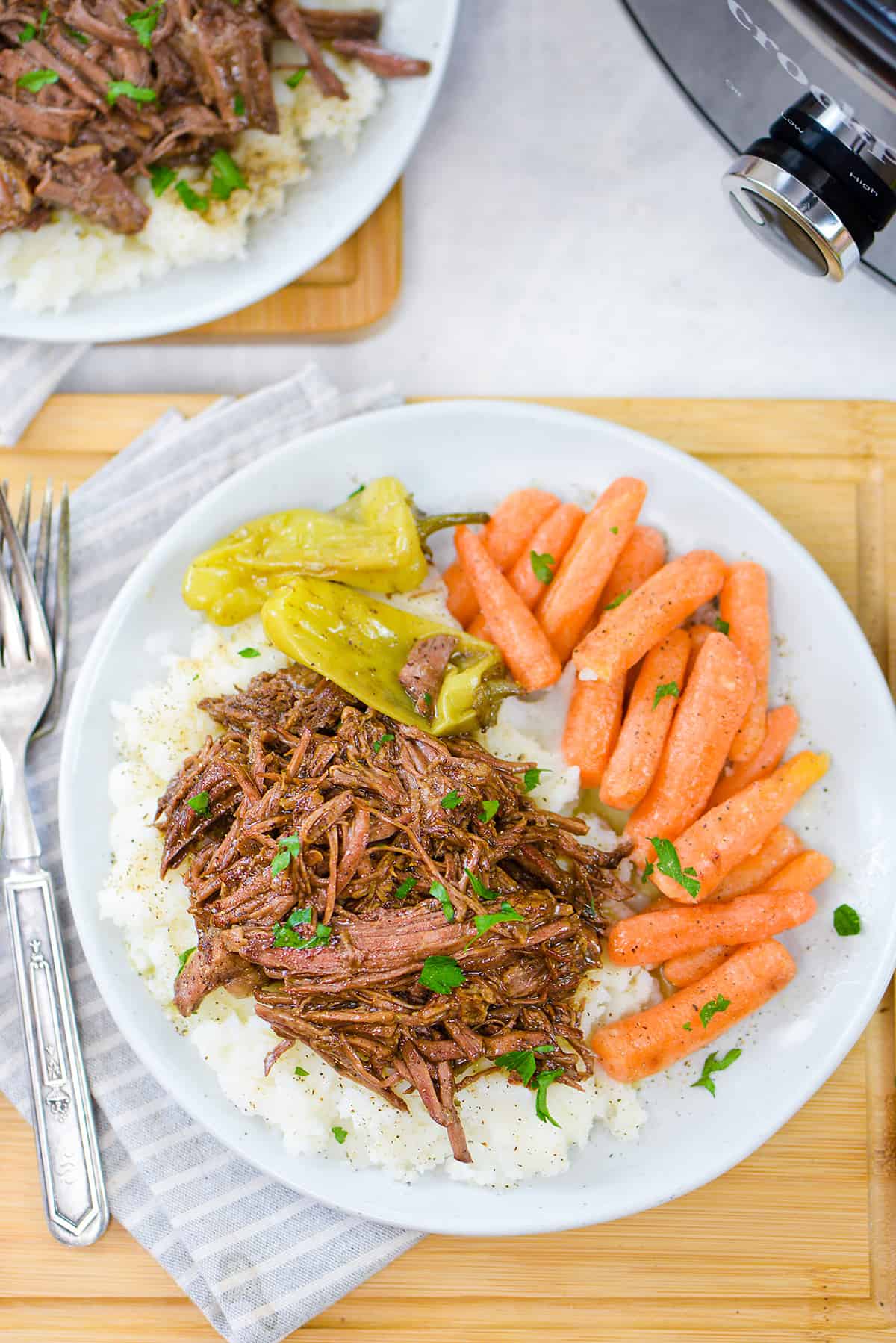 Mississippi Pot Roast on plate with mashed potatoes and carrots.