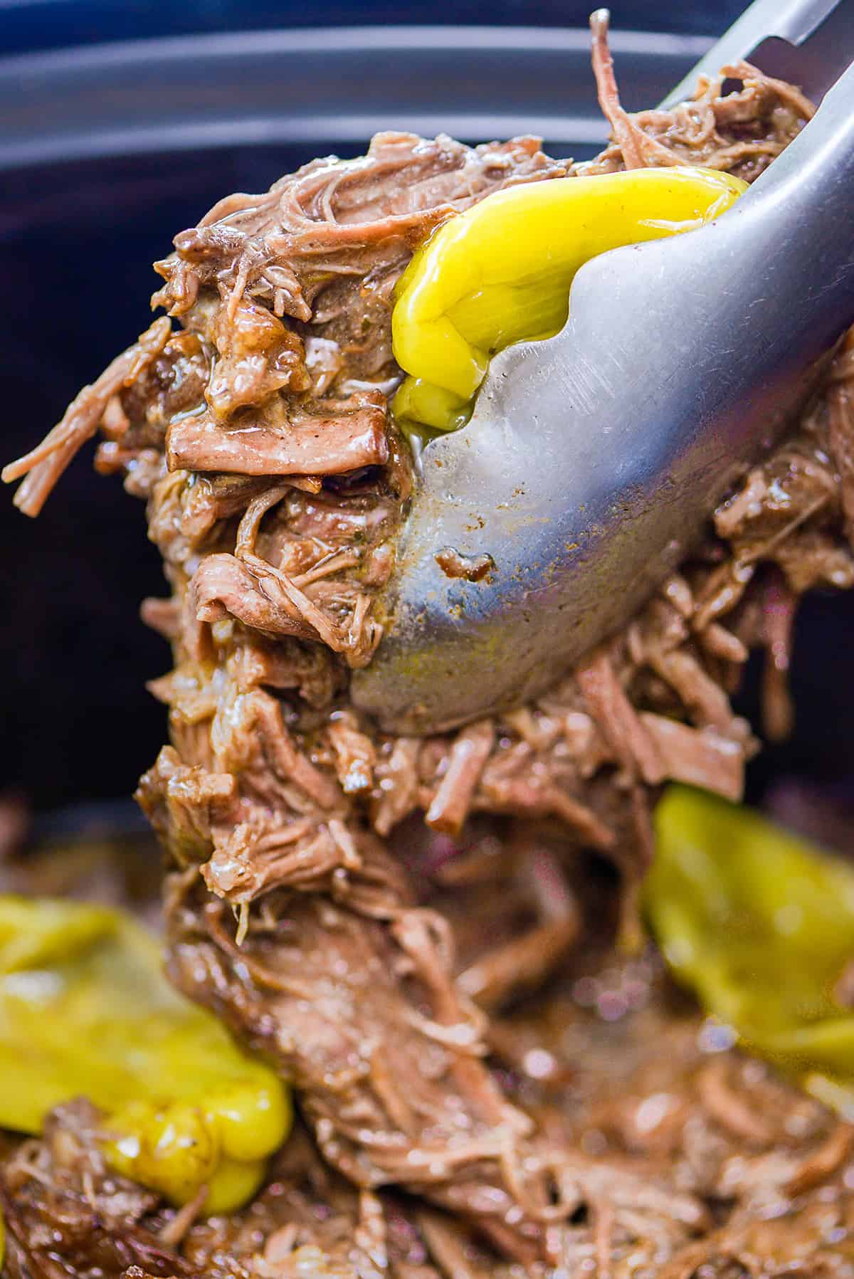 Shredded pot roast in tongs.