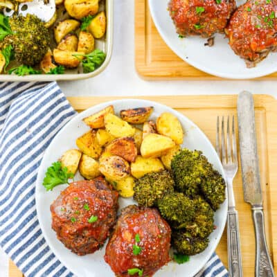 Mini meatloaves and veggies on white plate.