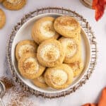 Overhead view of plate loaded with pumpkin thumbprint cookies.