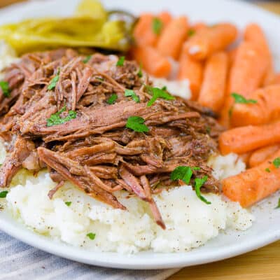 pot roast on plate with carrots and potatoes.