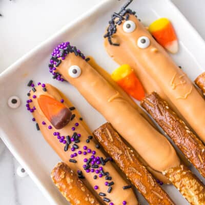 Pretzel rods with Halloween decorations on white plate.