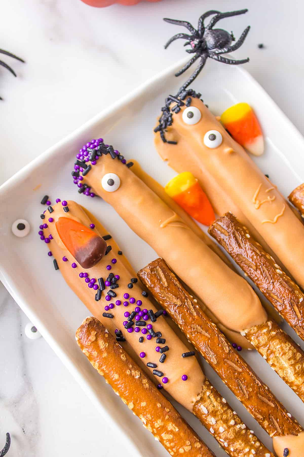 Pretzel rods with Halloween decorations on white plate.