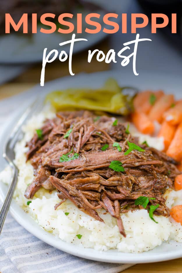 Crockpot Mississippi roast on plate with mashed potatoes and carrots.