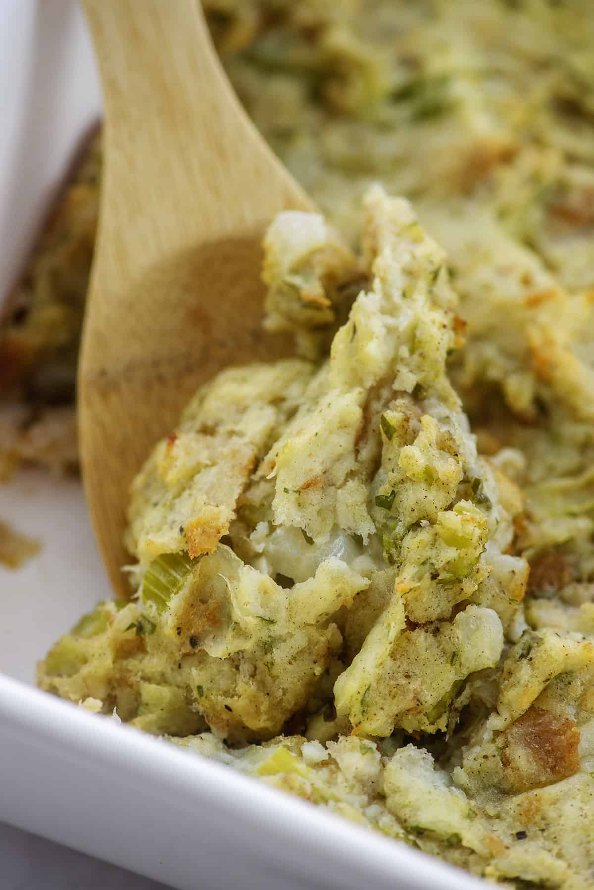 Mashed potato stuffing in dish on wooden spoon.